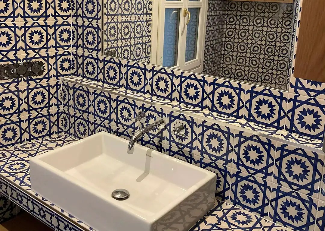 Lavabo encastré avec des carreaux décoratifs bleus et blancs, installé par Mgeau à Pontoise 95, avec un miroir au-dessus